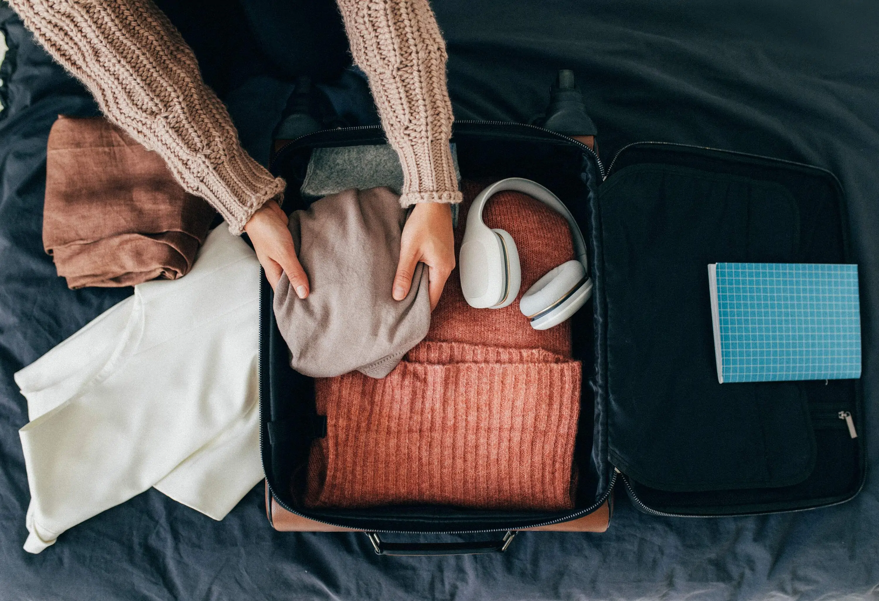 An individual arranges a luggage full of clothes.